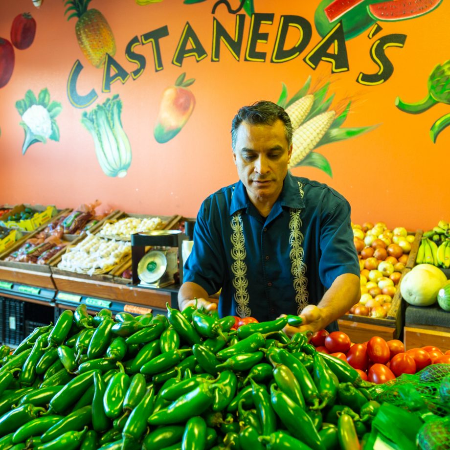 A market stall owner standing by his fruit