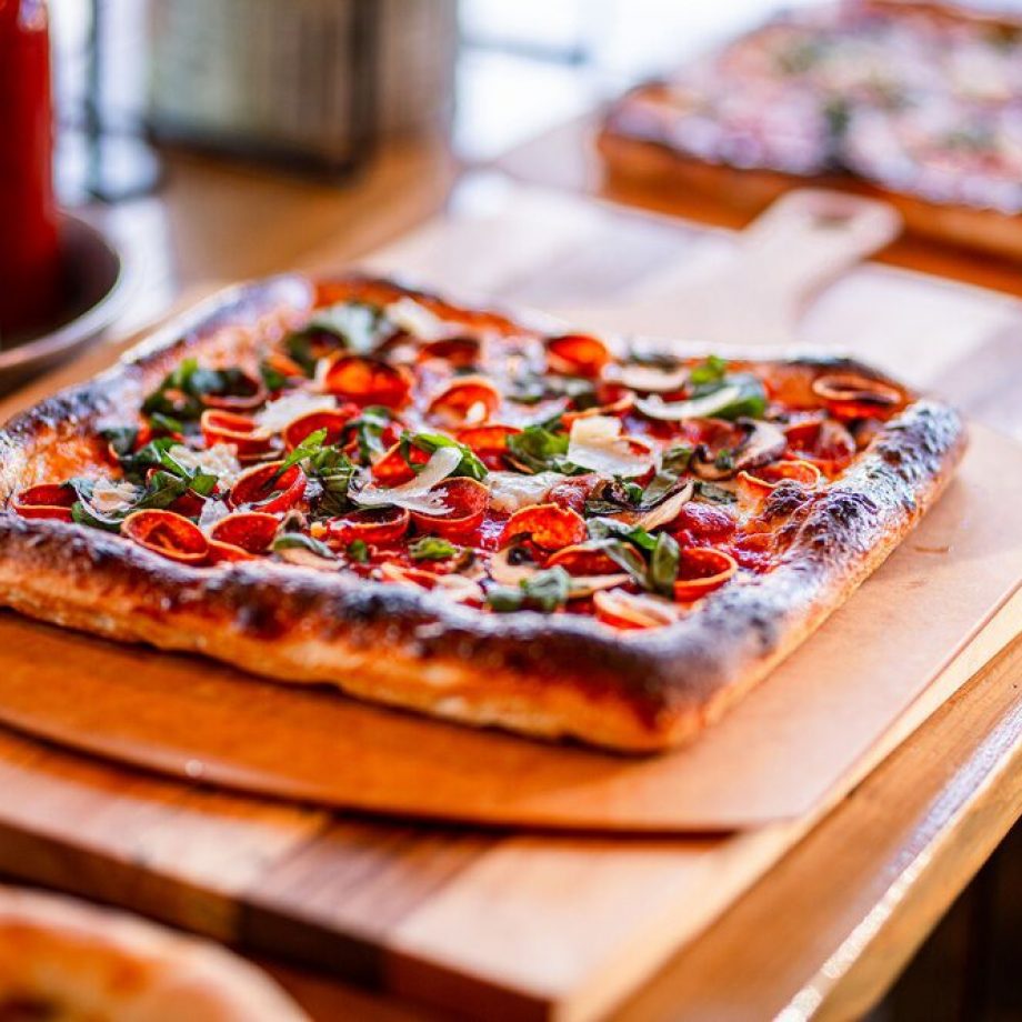 A square pizza on a wooden serving board